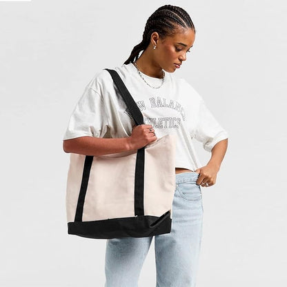 The image features a black cat positioned on the front of a white tote bag, creating a striking contrast in colors.