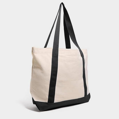 A black cat is displayed on the front of a white tote bag, highlighting its elegant silhouette against the bright fabric.
