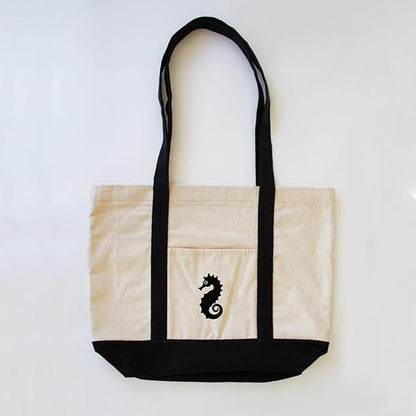 A stylish black and white tote bag featuring a seahorse design, perfect for beach days or casual outings.