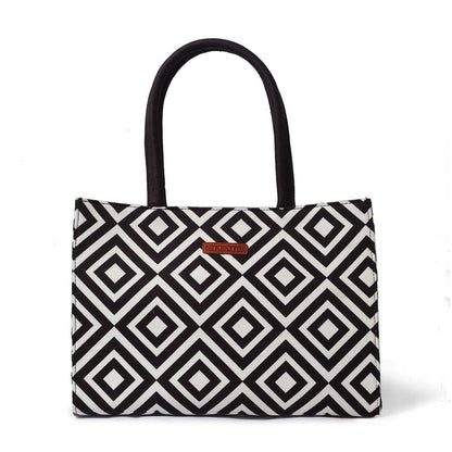 A stylish black and white bag with a book and a glass of water inside.