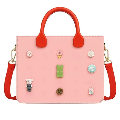 Pink handbag with red handles and strap, featuring various decorative pins on a white background.