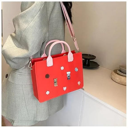 Red handbag with pink handles held by a person wearing a gray coat.