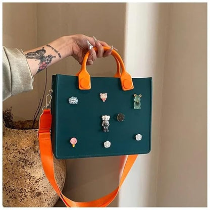 Teal handbag with orange handles and strap held by a person, featuring various small figurines attached.