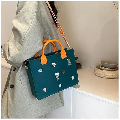 Teal handbag with orange handles and decorative pins worn by a person in a gray coat.