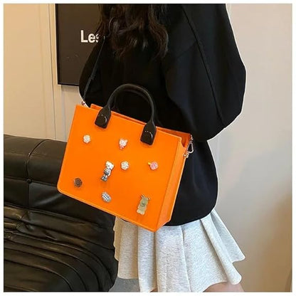 Orange handbag with decorative pins held by a person wearing a black jacket and white skirt.