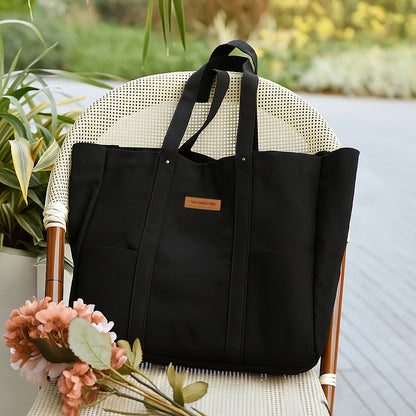 Black tote bag on a chair with flowers and plants in the background