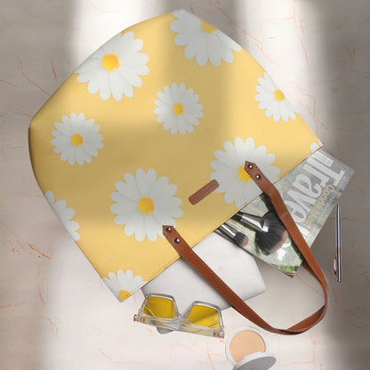 Bright yellow tote bag featuring delicate white daisies, a fashionable accessory for any outfit.