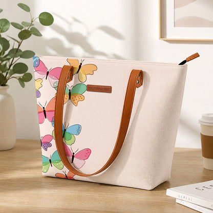 Beige tote bag with colorful butterfly pattern on a wooden surface.