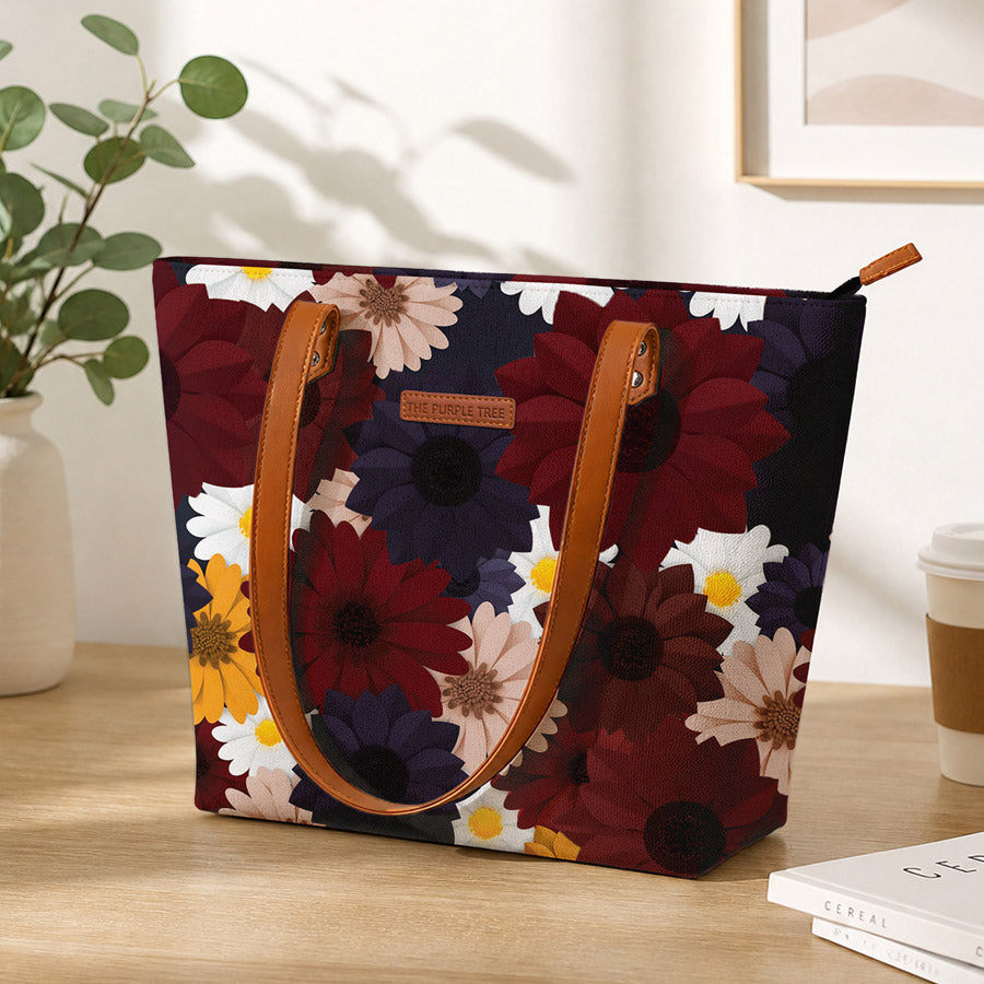 Floral-patterned TOTE BAG OR handbag with brown handles on a wooden surface, with a plant and coffee cup in the background.