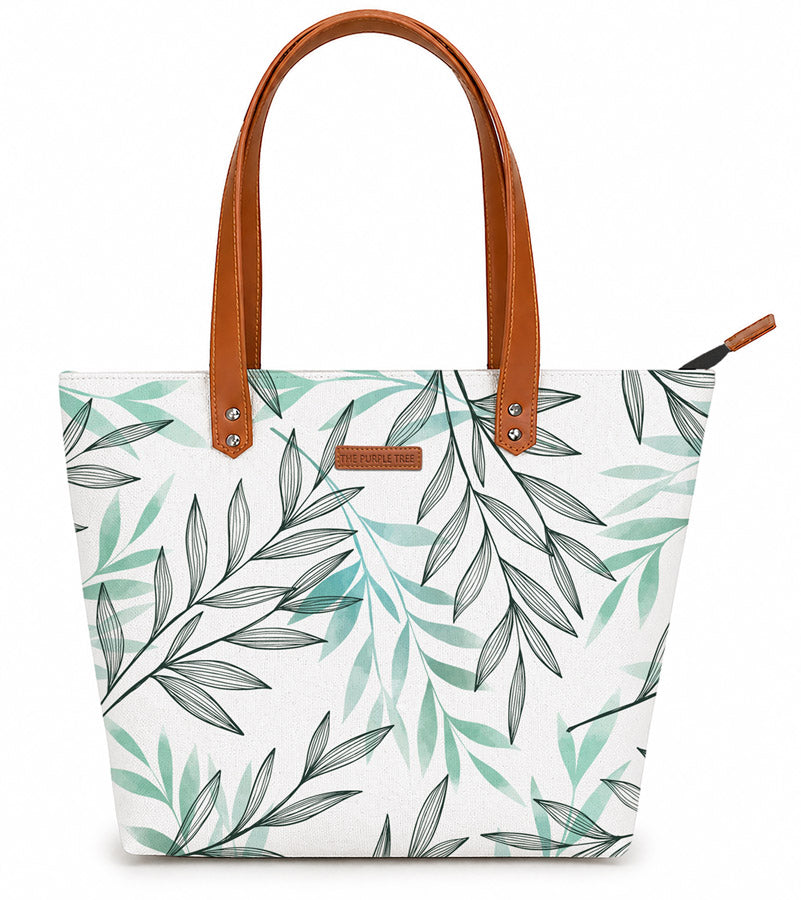 Tote bag with leaf pattern and brown handles on a white background