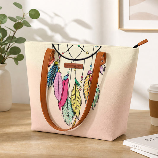Beige tote bag with dreamcatcher design on a wooden surface with a plant and coffee cup in the background.