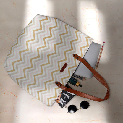 A stylish tote bag with a pink and gold chevron pattern, perfect for adding a touch of glam to your outfit!