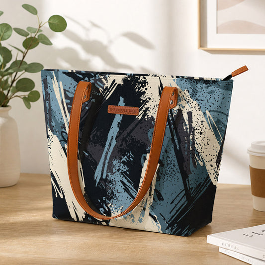 Tote bag with abstract design on a wooden surface with a plant and coffee cup in the background
