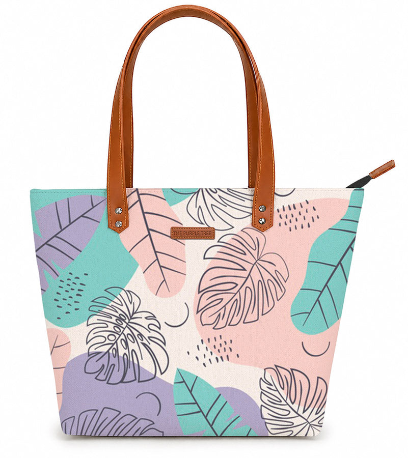 Tote bag with tropical leaf pattern and brown handles on a white background