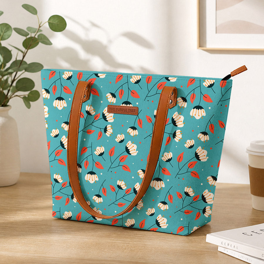 Floral-patterned tote bag with brown handles on a wooden surface.