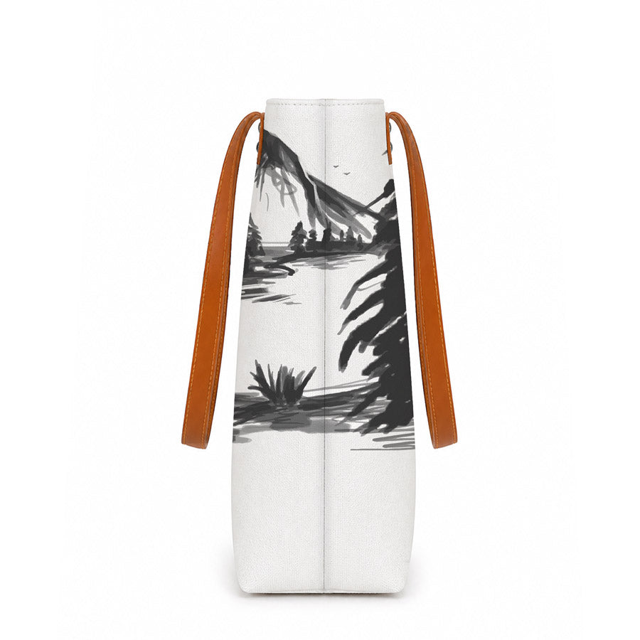 White bag with black mountain and palm tree design and brown straps on a white background