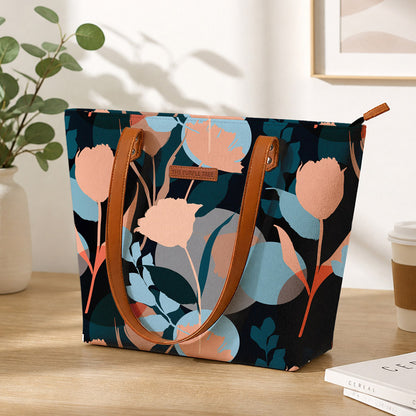 Floral-patterned tote bag on a wooden surface with a plant and coffee cup in the background