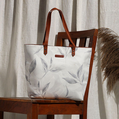 A stylish tote bag with a white and gray leaf print design.