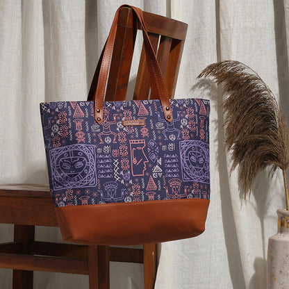 A stylish purple and brown tote bag resting on a chair.