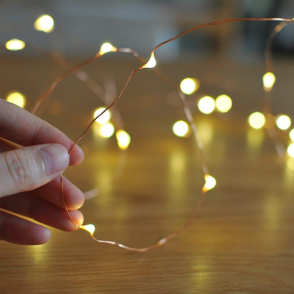 Individual with string lights on tabletop.