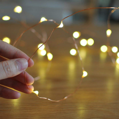 A person placing string lights on a table.