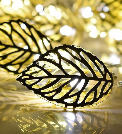 An elegant vase holding a beautiful arrangement of flowers illuminated by delicate lights.