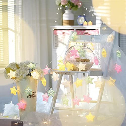 Cozy room featuring a bed, a lamp, and a table adorned with a decorative star garland.
