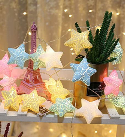 Comfortable room containing a bed, a lamp, and a table draped with a festive star garland.