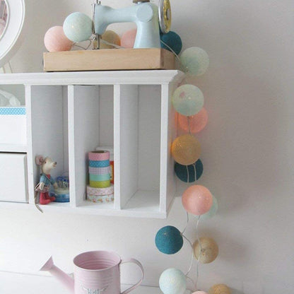 Colorful ball string lights drape elegantly on the wall, bringing a playful element to the room.