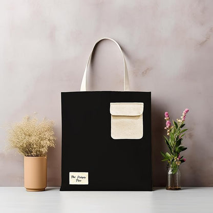 A stylish black and white tote bag featuring a prominent white pocket for added functionality and design appeal.