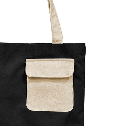A fashionable black and white tote bag that includes a striking white pocket, ideal for carrying essentials with elegance.
