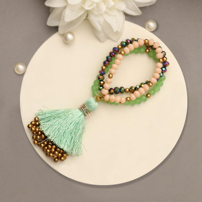 A decorative bracelet featuring a tassel and beads elegantly displayed on a wooden table surface.