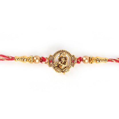 A gold rakhi bracelet featuring a Hindu god.
