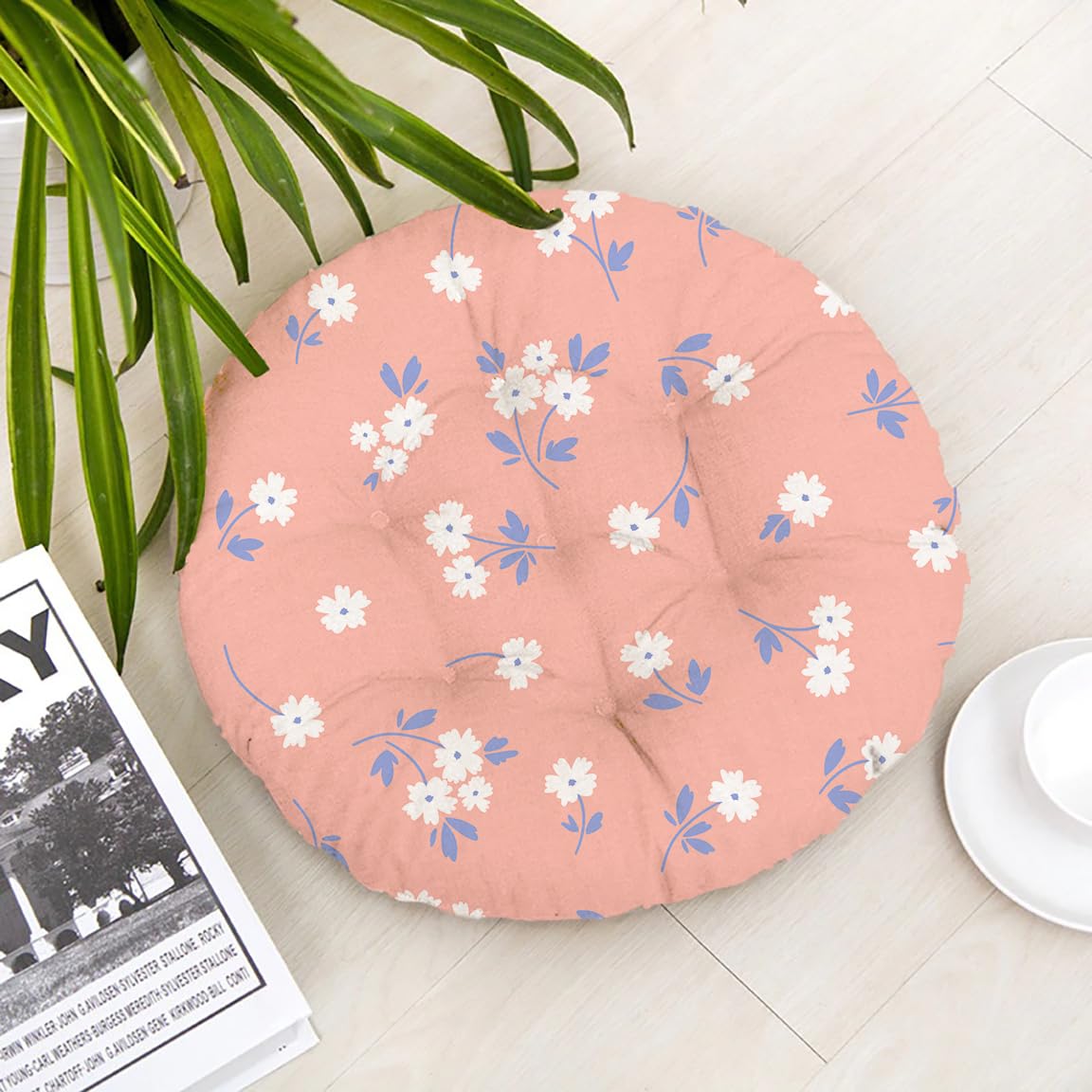A round floor pillow adorned with vibrant pink flowers against a neutral background.