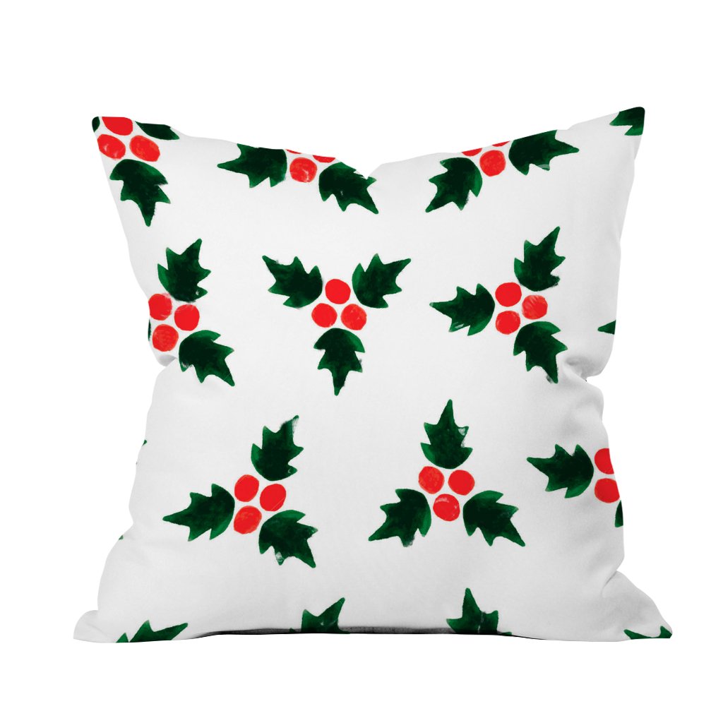 A white pillow adorned with vibrant red holly leaves and berries, perfect for festive decor.