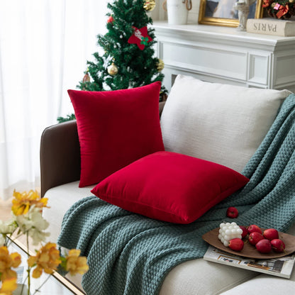 A couch featuring two red pillows is positioned near a Christmas tree, adding a touch of holiday cheer to the room.