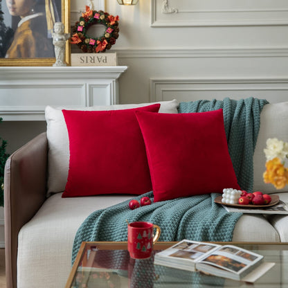  Two red pillows are placed on a couch adjacent to a Christmas tree, contributing to a warm and festive setting.