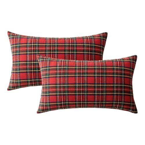  A couch adorned with two red plaid pillows sits next to a festive Christmas tree, creating a warm holiday atmosphere.