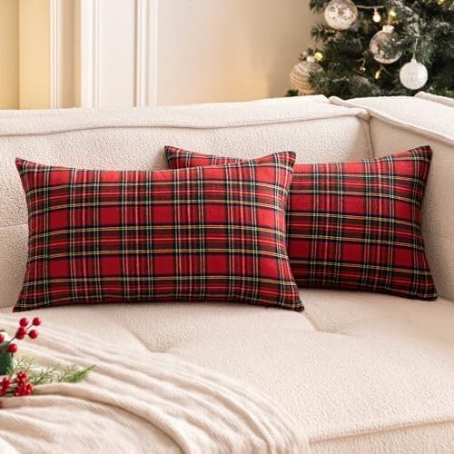 Two cozy red plaid pillows rest on a couch beside a beautifully decorated Christmas tree.