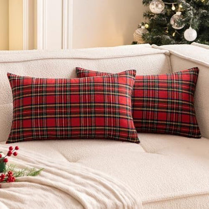 Two cozy red plaid pillows rest on a couch beside a beautifully decorated Christmas tree.