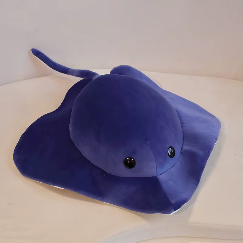 Blue plush toy shaped like a blue Sting ray on a white surface