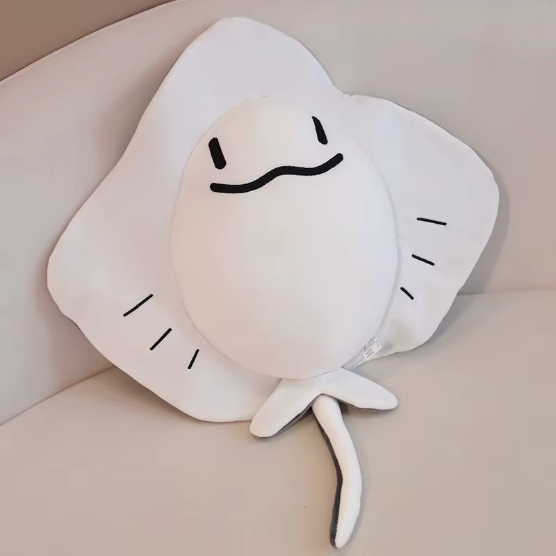 White plush Sting ray toy with a smiley face on a beige surface