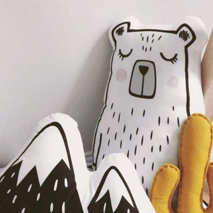 A hand holding a bear pillow on a white background.