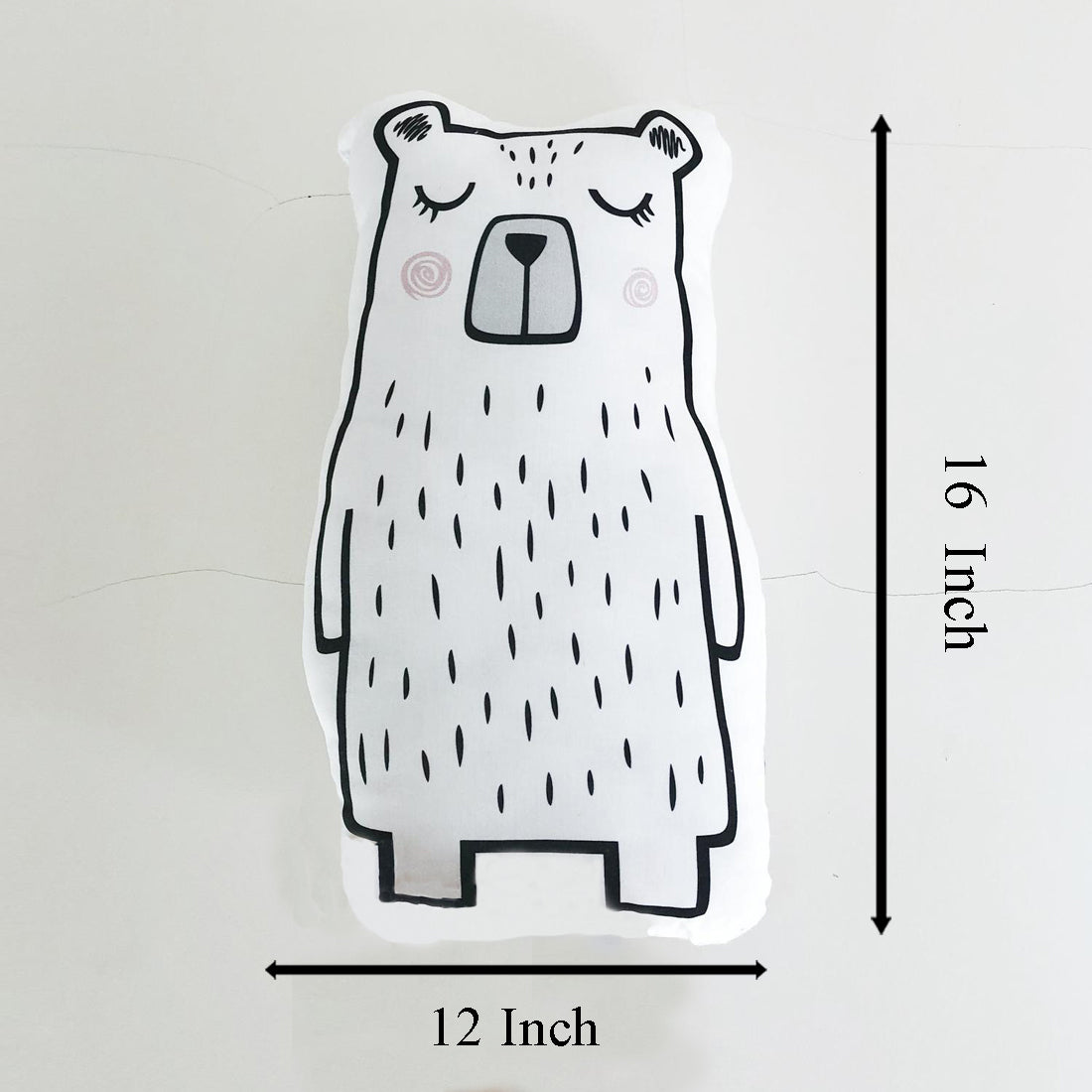 A hand holding a bear pillow against a white background.