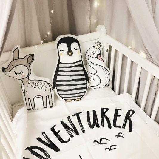 1. A baby's crib with white bedding and a black and white pillow.
