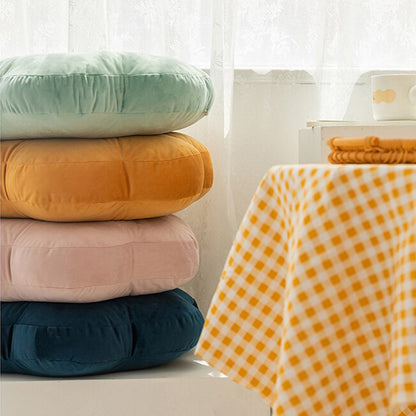 Pile of pillows on table near yellow and blue checkered tablecloth.