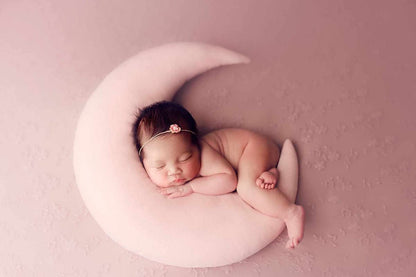A peaceful newborn girl sleeping on a pink pillow
