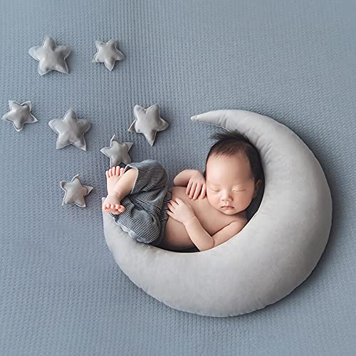 A peaceful newborn rests on a crescent-shaped pillow adorned with stars.