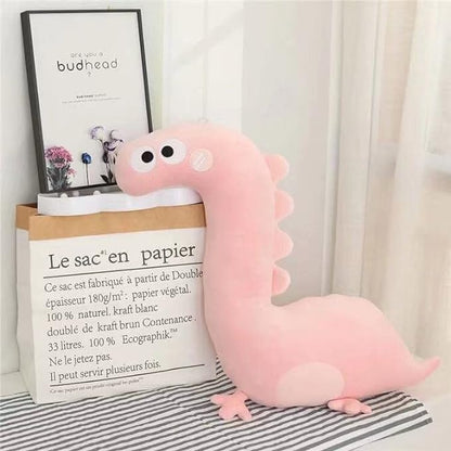 Pink dinosaur plushie sitting on a bed