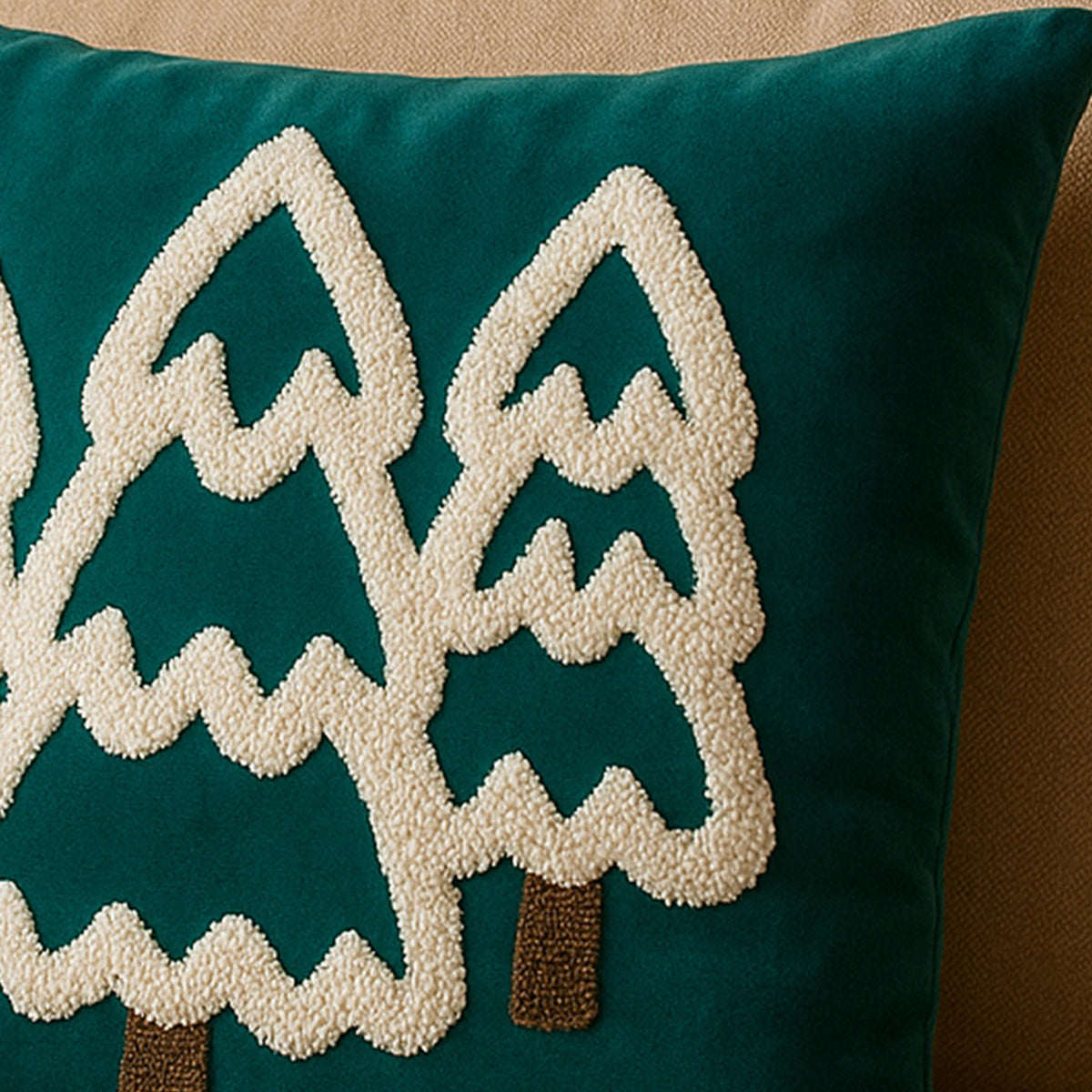 Teal pillow with embroidered trees on a beige background